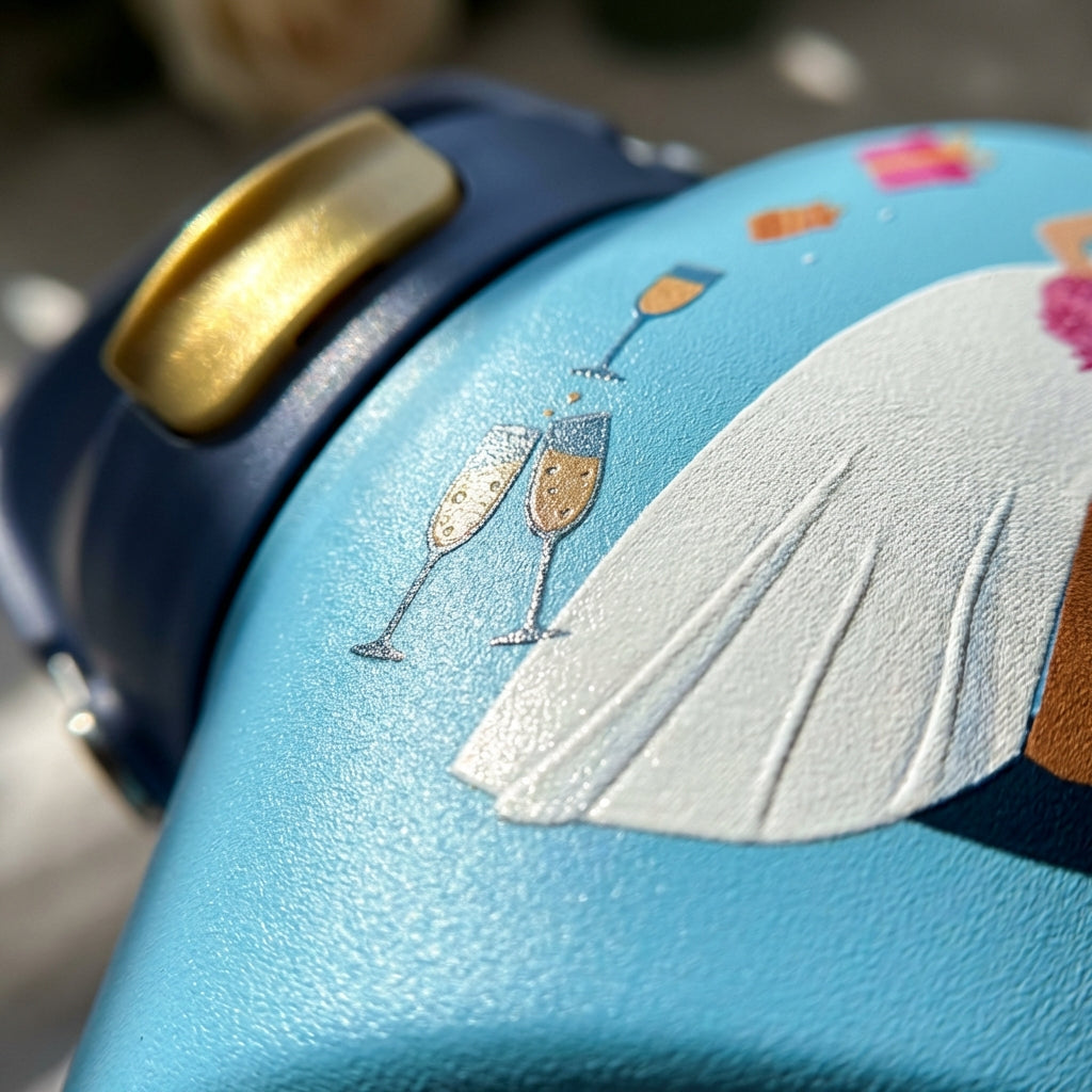 Detail shot - Light blue Cascade 40oz insulated tumbler featuring a bride and groom illustration, champagne glasses, and balloons on a rustic wooden table.