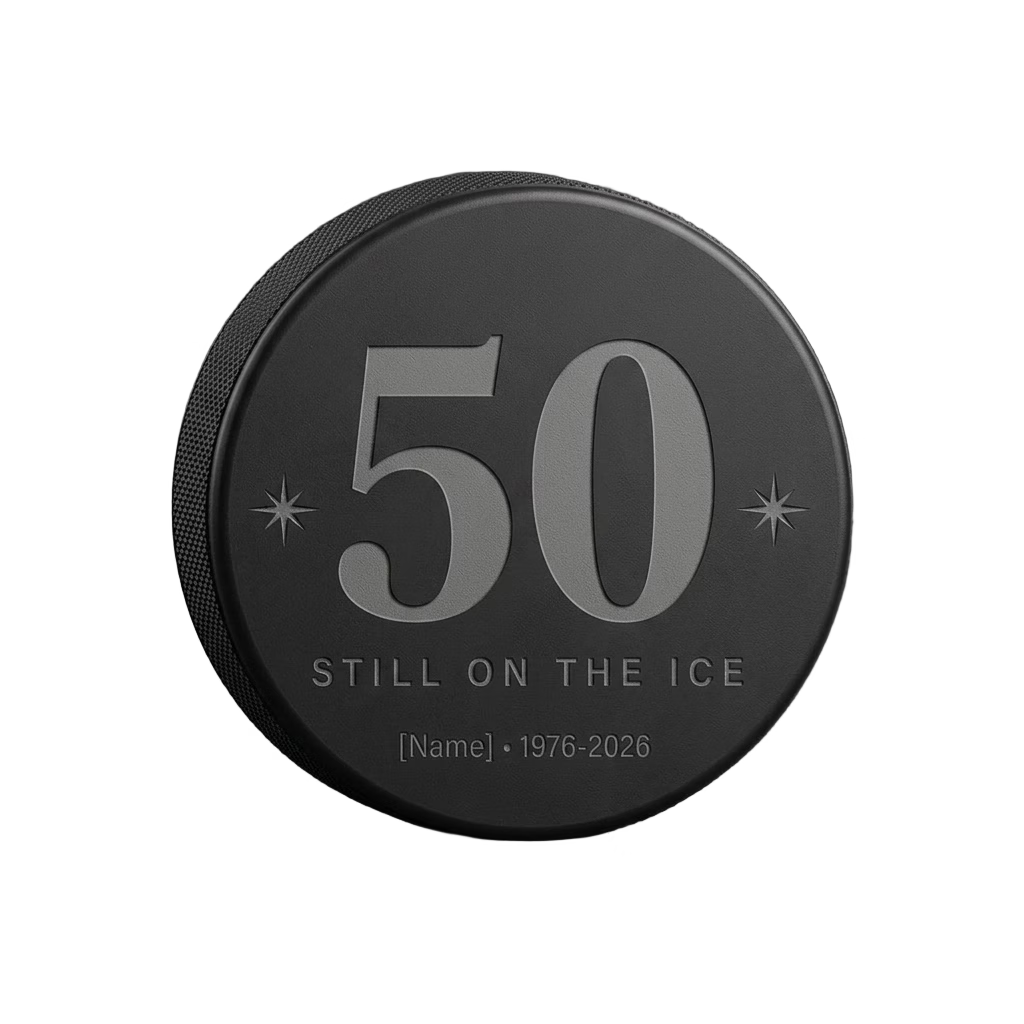 "50 Still on the Ice" Hockey Birthday Engraved Puck — laser-engraved hockey puck, tonal black-on-black engraving on vulcanized rubber, made in Calgary