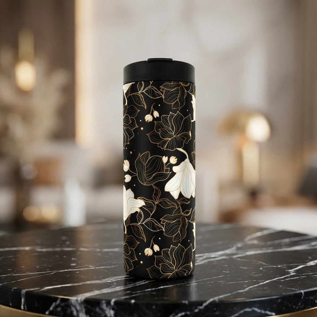 Grouse 16 oz insulated tumbler with black background and metallic gold floral outlines sitting on a marble countertop.