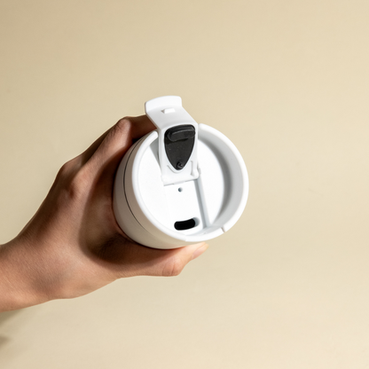 LAMOSE white replacement bottle lid with black flip-top closure, held in hand. Top view showing spout and vent for Grouse Collection.