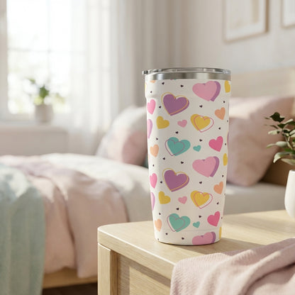 LAMOSE Peyto 16oz travel tumbler in white featuring a colorful pattern of pink, purple, teal, and orange confetti hearts on a bedroom nightstand.