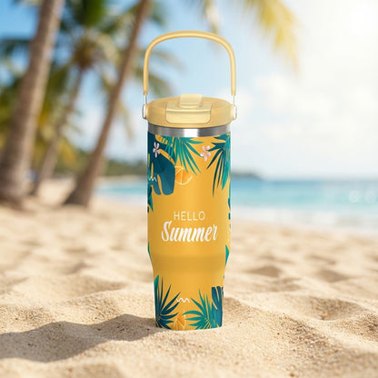 Yellow 40 oz Cascade tumbler sitting on white sand beach featuring Hello Summer text, tropical leaves, orange fruit segments, and pink flowers.
