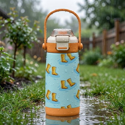 LAMOSE Goose 14oz kids water bottle featuring yellow rain boots pattern on light blue background with orange handle, sitting on wet grass with rain droplets.