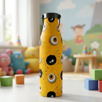 Close up of a vibrant yellow LAMOSE Robson 21 oz bottle with a pattern of cartoon black spiders and eyeballs, sitting on a white table in a sunlit playroom.