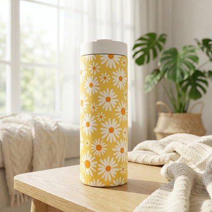 LAMOSE Grouse 16 oz yellow insulated tumbler with white daisy pattern sitting on a rustic wooden table in a sunlit room.
