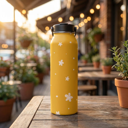 LAMOSE Grouse 34 oz yellow insulated tumbler with white daisy floral and polka dot pattern sitting on a wooden outdoor table.