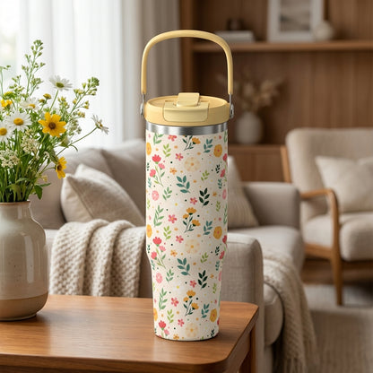 Close up of 40oz cream tumbler with pink and yellow floral pattern and yellow handle sitting on wooden surface.