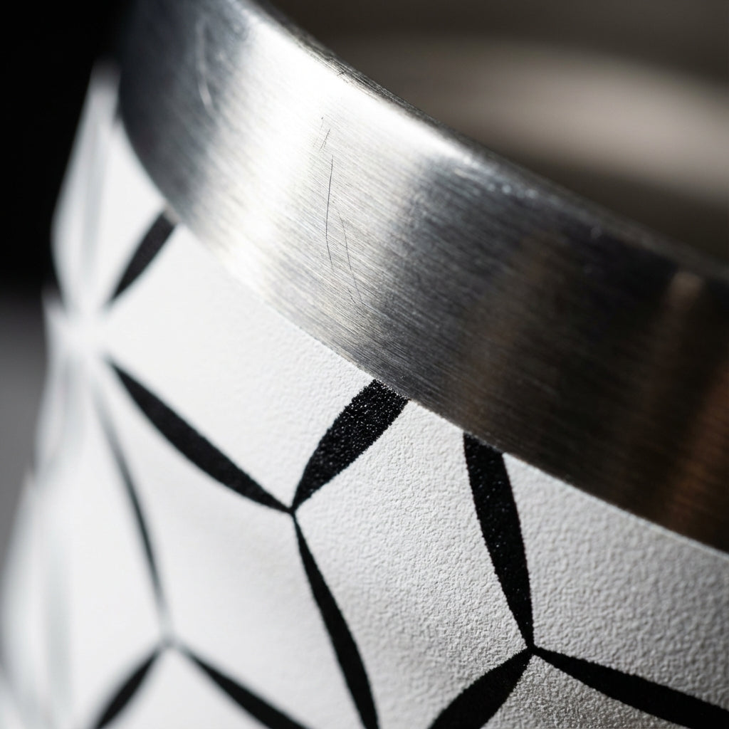 Detail shot - Peyto 16oz tall tumbler featuring black geometric starburst pattern on white background sitting on a marble table