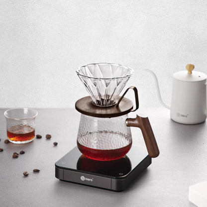 LAMOSE zeroHero Walnut Prisma pour-over coffee dripper and server set with faceted glass and wood accents, on a brewing scale, with a white kettle and coffee beans.