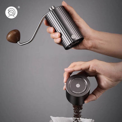 LAMOSE zeroHero Z3 Pro hand coffee grinder in dark grey with ribbed metal body, wooden handle, held grinding coffee into a filter.