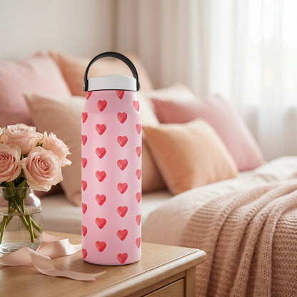 LAMOSE Grouse 34 oz insulated water bottle featuring a light pink background with a geometric faceted red heart pattern, white lid, and black handle.