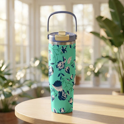 LAMOSE Cascade 40 oz stainless steel tumbler featuring a light teal background with dark blue and white floral pattern sitting on a wooden table in a sunlit room.