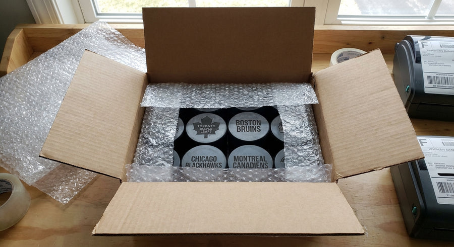 Open shipping box with bubble wrapped laser engraved hockey pucks fulfillment