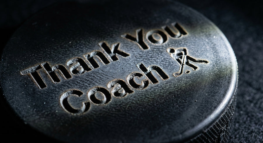 Extreme close-up macro of Thank You Coach laser engraving on black rubber puck