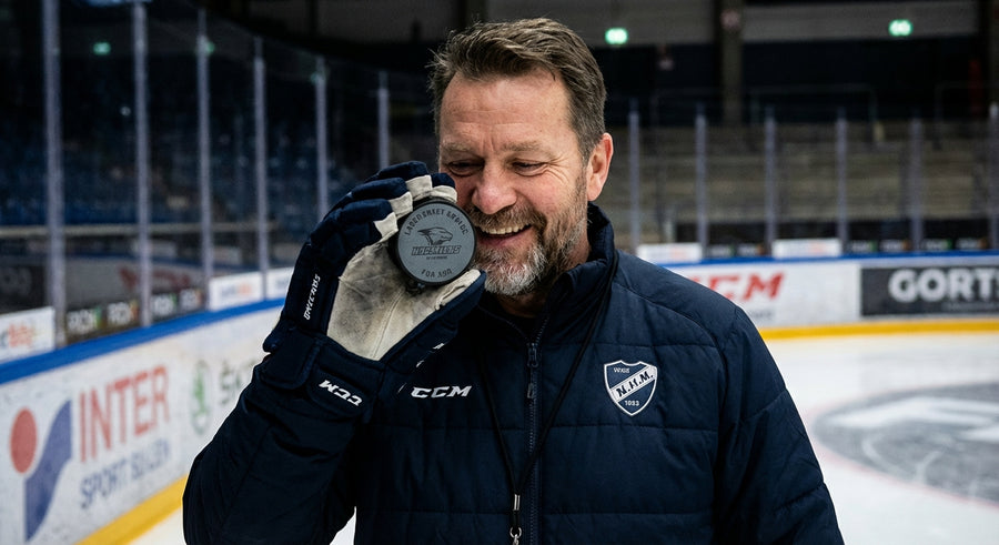 Hockey coach holding custom engraved puck at arena rink