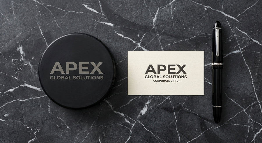 Overhead flat lay engraved hockey puck on marble with business card and fountain pen