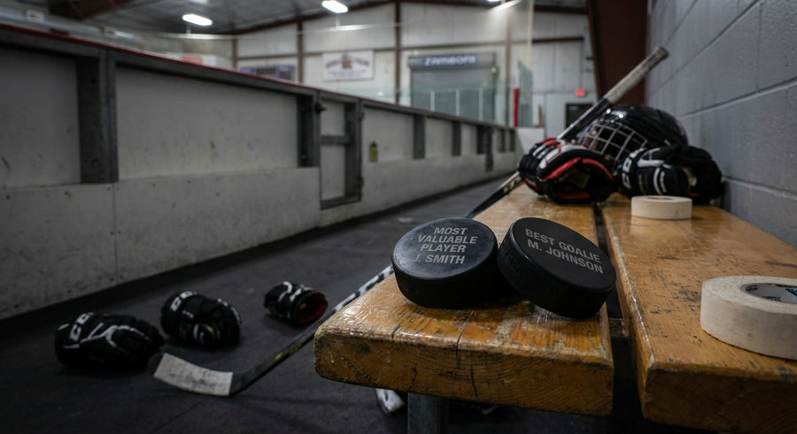 Two engraved hockey pucks on arena bench Most Valuable Player Best Goalie