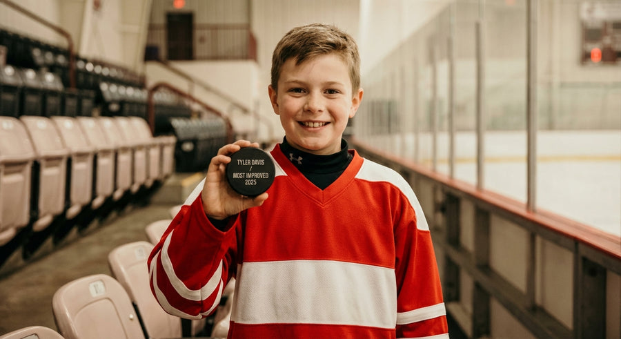 Young hockey player proudly holding laser engraved puck at arena