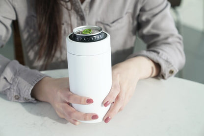 LAMOSE Logan 16 oz white stainless steel can cooler, front view, held by hands, with an open 'TAURINE' beverage can.