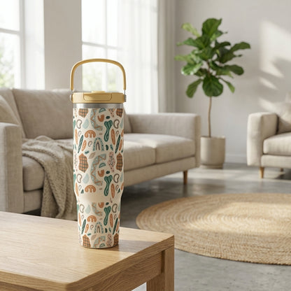 Tan 40 oz tumbler with yellow handle featuring abstract geometric shapes in brown, green, and light blue sitting on a wooden surface