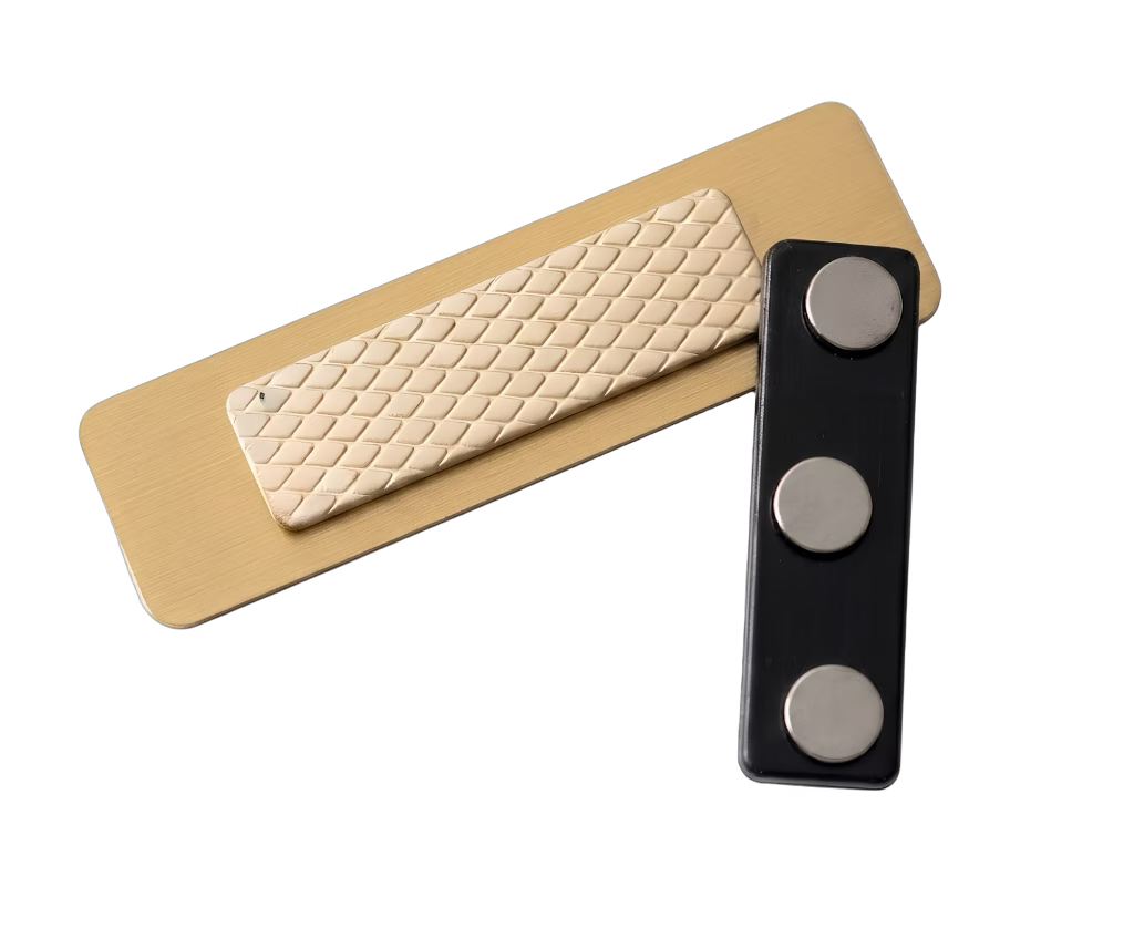 Salon & Spa Name Tag — Stylist / Therapist / Receptionist (Custom) attachment system — gold-laminate name tag with textured adhesive pad and separate three-magnet housing in dark plastic. The two pieces sandwich the fabric for a secure hold with no pin holes. Made by LAMOSE in Calgary, Canada.