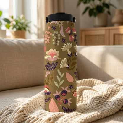 Close-up of olive green 34oz insulated water bottle featuring pink and purple botanical wildflower pattern resting on a beige knit blanket.