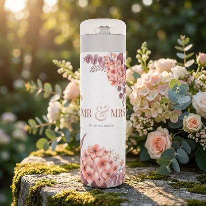 White 16oz travel tumbler featuring pink and peach watercolor floral design with Mr & Mrs Are Getting Married text and fresh water droplet details